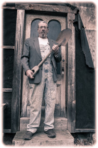 Man with shovel standing by wooden door.